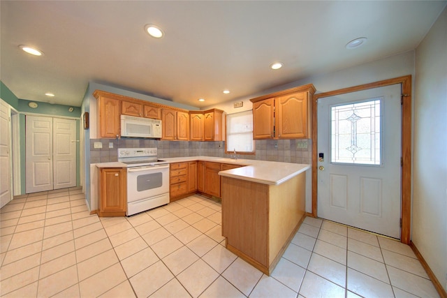 kitchen featuring a peninsula, white appliances, tasteful backsplash, and light countertops