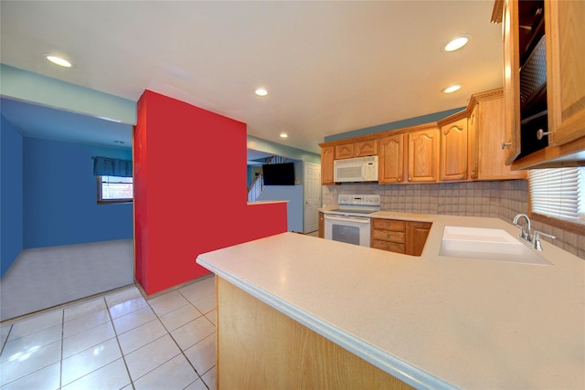 kitchen with light countertops, backsplash, a sink, white appliances, and a peninsula