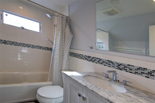 bathroom with visible vents, toilet, shower / bath combination with curtain, vanity, and tile walls