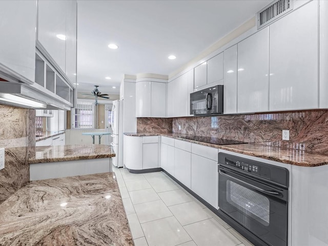 kitchen with tasteful backsplash, white cabinetry, light stone counters, and black appliances