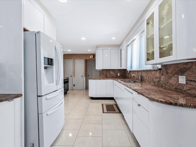 kitchen featuring sink, white appliances, light tile patterned floors, tasteful backsplash, and white cabinets