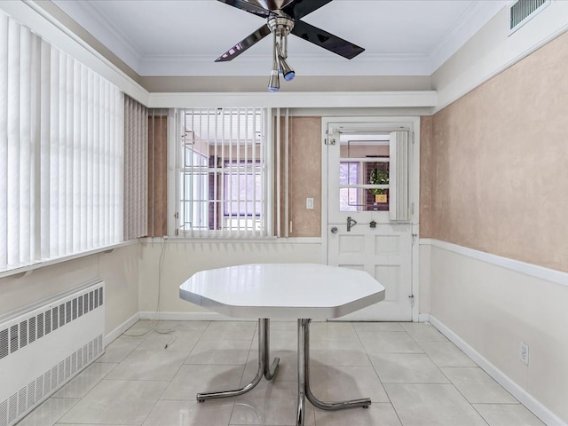 unfurnished dining area featuring crown molding, radiator heating unit, ceiling fan, and light tile patterned floors