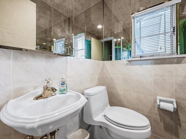 bathroom with sink, tile walls, and toilet