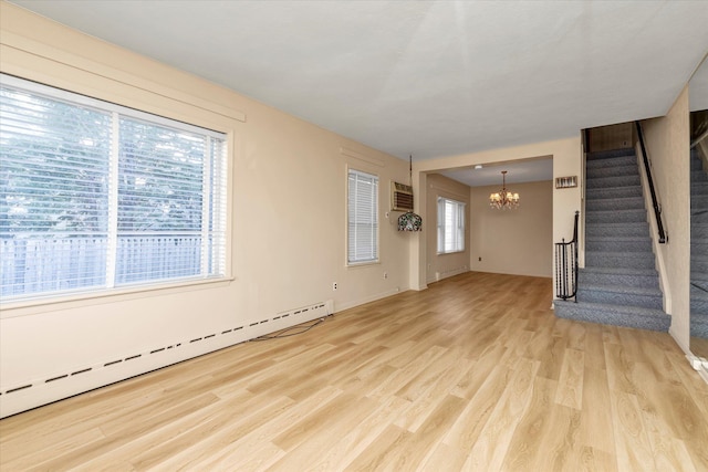 unfurnished living room featuring an inviting chandelier, a baseboard radiator, a wall unit AC, and light wood-type flooring