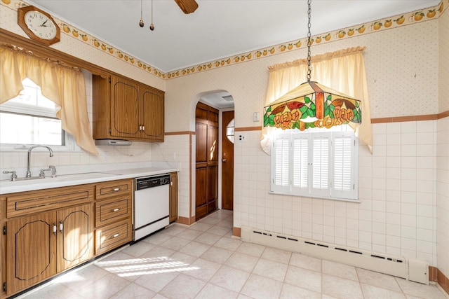 kitchen with sink, decorative light fixtures, tile walls, a baseboard radiator, and white dishwasher