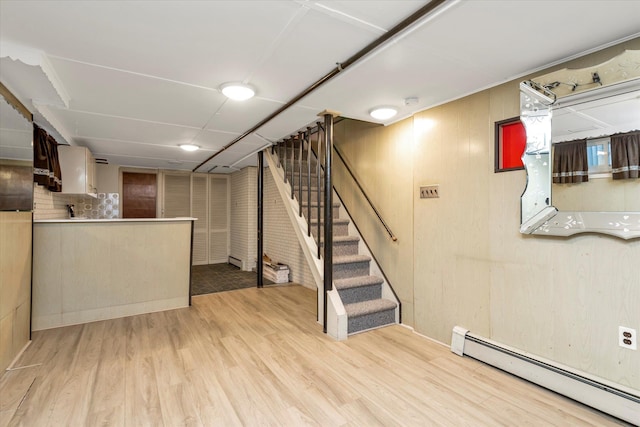 basement featuring a baseboard heating unit and light wood-type flooring