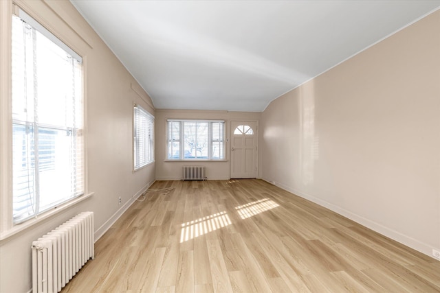 empty room featuring radiator heating unit, light hardwood / wood-style flooring, and plenty of natural light