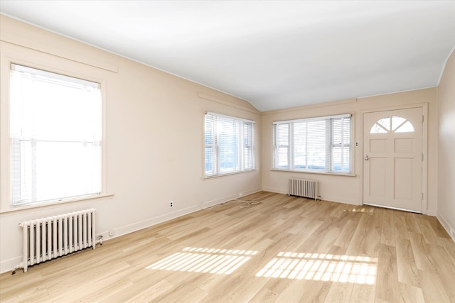 foyer featuring lofted ceiling, radiator, and light wood-type flooring