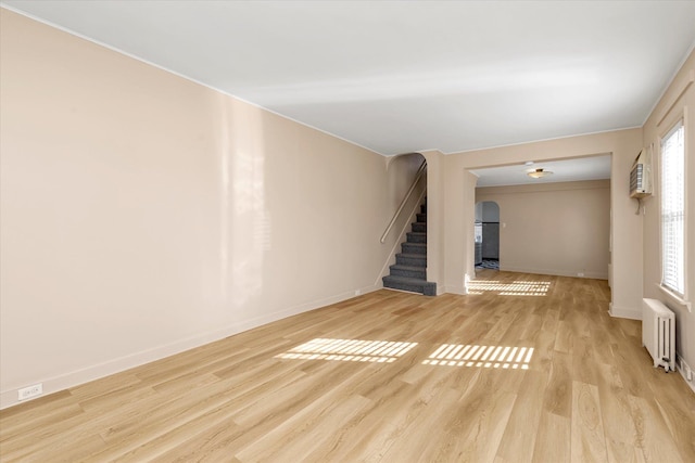 unfurnished living room featuring radiator and light wood-type flooring