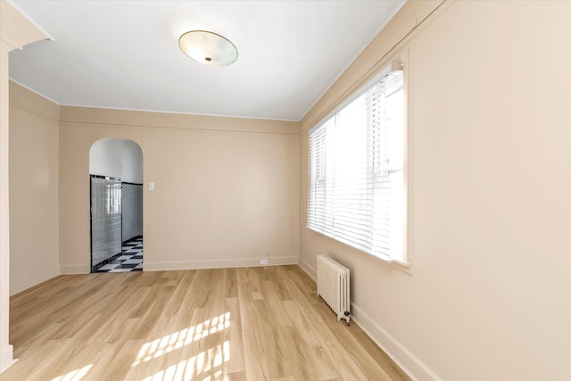 empty room with radiator heating unit and light wood-type flooring