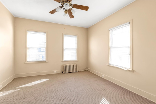 spare room featuring ceiling fan, radiator heating unit, and light carpet