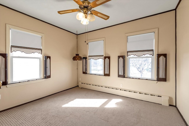 carpeted spare room with crown molding, ceiling fan, and baseboard heating