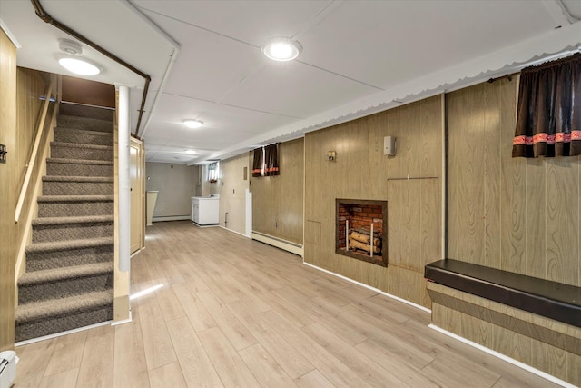 basement with baseboard heating, wood walls, and light wood-type flooring