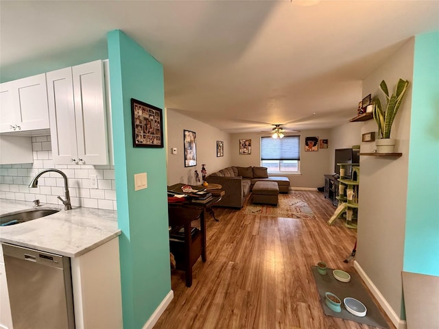 interior space featuring sink, white cabinetry, tasteful backsplash, light stone counters, and dishwasher