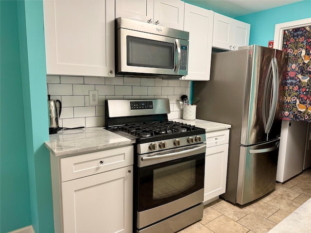 kitchen with decorative backsplash, light stone countertops, white cabinets, and appliances with stainless steel finishes