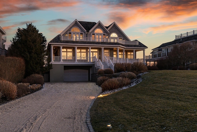 view of front of house with a yard, a garage, a balcony, and a porch