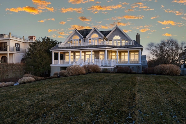 view of front facade with a lawn, a balcony, and a porch