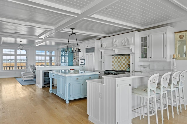 kitchen featuring a breakfast bar, hanging light fixtures, a kitchen island, and white cabinets