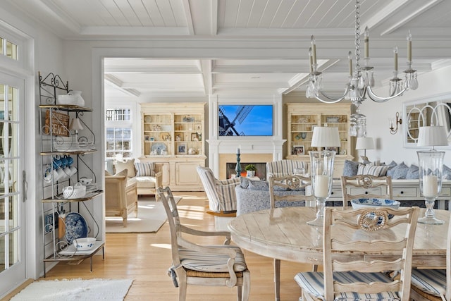 dining room featuring built in shelves, crown molding, a chandelier, light wood-type flooring, and beamed ceiling