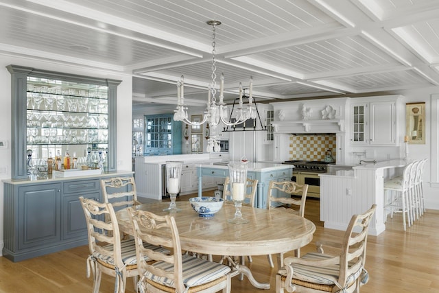 dining space with beamed ceiling, coffered ceiling, a notable chandelier, and light hardwood / wood-style floors