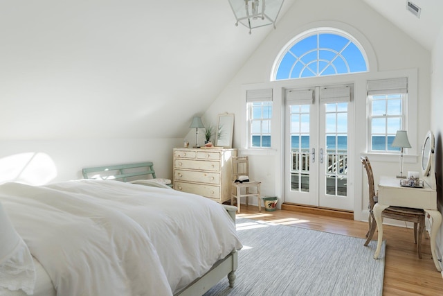 bedroom with french doors, lofted ceiling, a water view, access to exterior, and light hardwood / wood-style floors