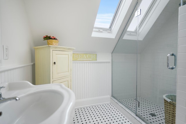 bathroom with sink, a shower with shower door, and vaulted ceiling with skylight