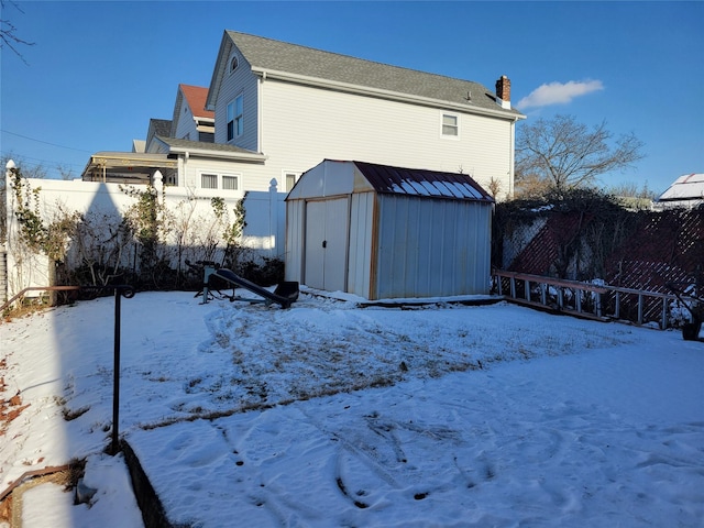 snow covered house featuring a storage unit