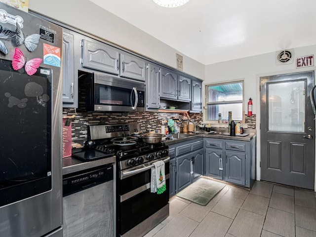 kitchen featuring tasteful backsplash, gray cabinetry, and appliances with stainless steel finishes