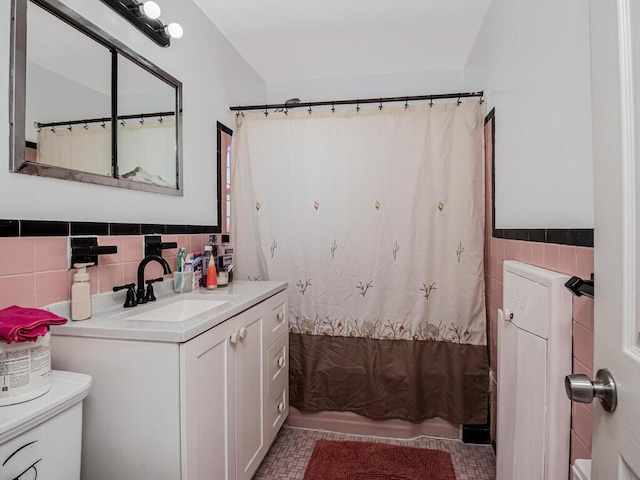 full bathroom with shower / tub combo with curtain, toilet, tile walls, vanity, and tile patterned flooring