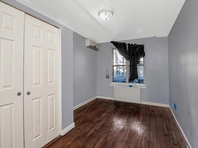 interior space with dark hardwood / wood-style flooring, a wall mounted air conditioner, radiator heating unit, and a closet