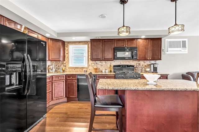 kitchen featuring decorative light fixtures, tasteful backsplash, a wall mounted AC, a center island, and black appliances