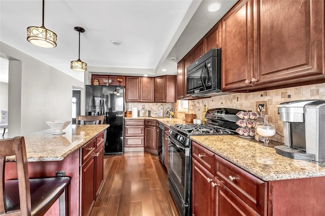 kitchen with light stone counters, hanging light fixtures, backsplash, dark wood-style floors, and black appliances