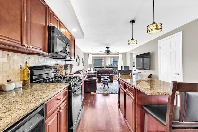 kitchen featuring light stone counters, dark wood-style flooring, open floor plan, backsplash, and black appliances