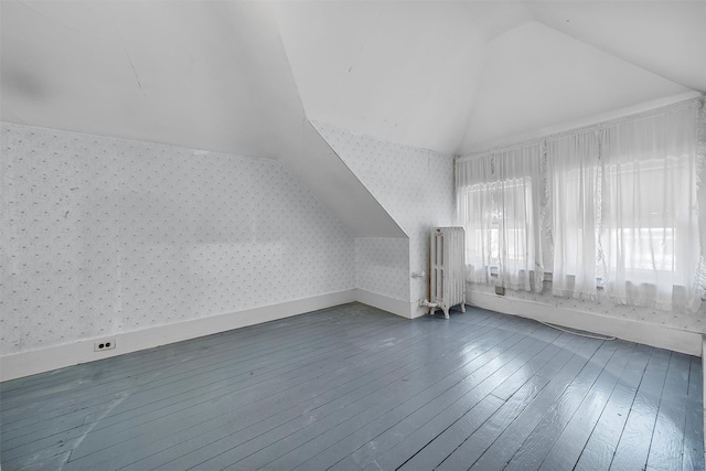 additional living space with hardwood / wood-style flooring, radiator heating unit, and vaulted ceiling