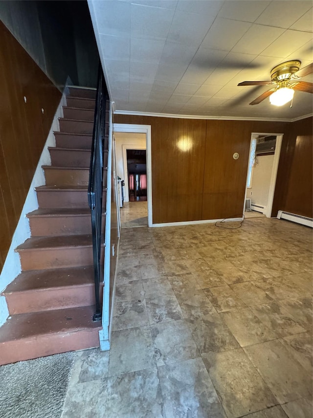 interior space with a baseboard heating unit, wooden walls, ornamental molding, and ceiling fan