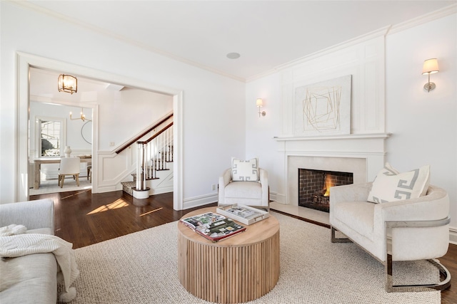 living room with an inviting chandelier, a fireplace, crown molding, and hardwood / wood-style floors