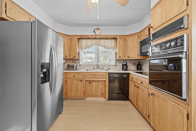 kitchen featuring sink, light hardwood / wood-style flooring, decorative backsplash, and black appliances