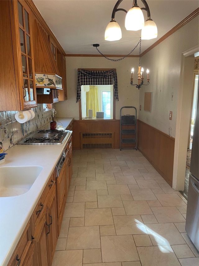 kitchen with sink, radiator heating unit, ornamental molding, stainless steel gas cooktop, and decorative light fixtures