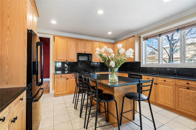 kitchen featuring a breakfast bar area, dark stone counters, a center island, light tile patterned floors, and black appliances