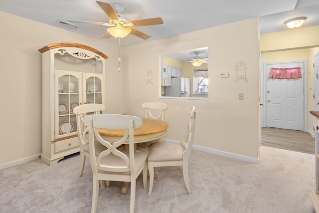 dining space featuring ceiling fan and light carpet