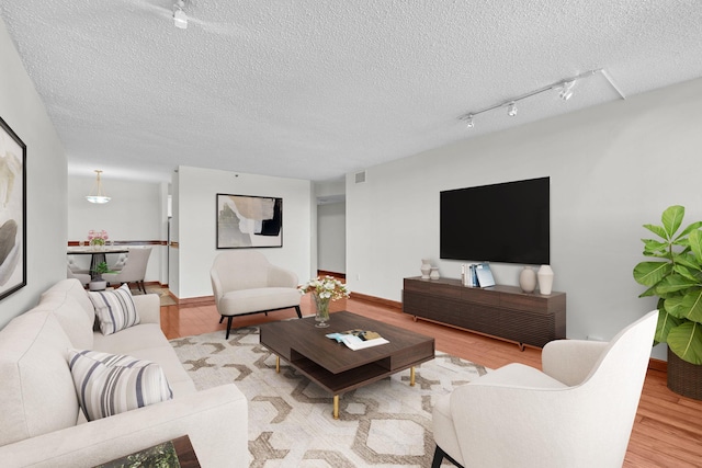 living area featuring visible vents, a textured ceiling, and wood finished floors