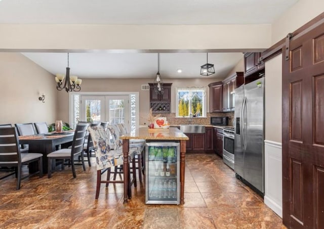 kitchen featuring wine cooler, stainless steel appliances, decorative light fixtures, and a kitchen island