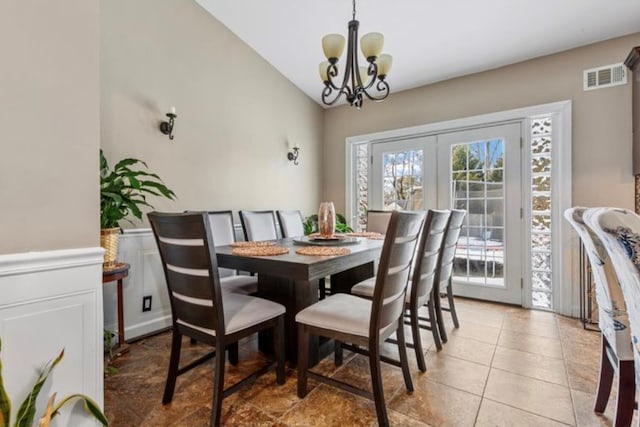 tiled dining area featuring a notable chandelier, vaulted ceiling, and french doors