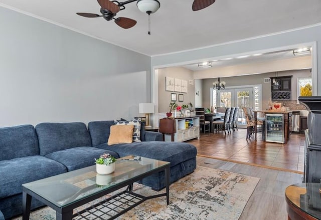 living room featuring dark hardwood / wood-style floors, ceiling fan with notable chandelier, and beverage cooler