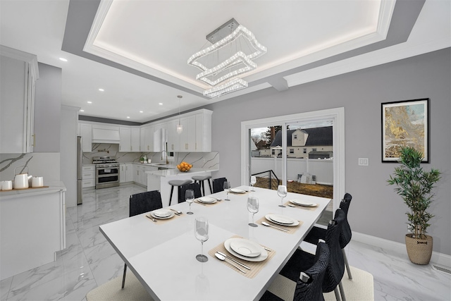 dining space featuring sink, a tray ceiling, ornamental molding, and a chandelier