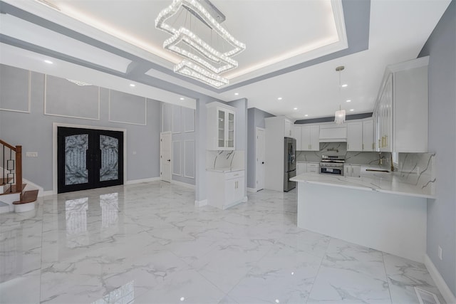 kitchen featuring appliances with stainless steel finishes, white cabinets, light stone counters, a raised ceiling, and french doors