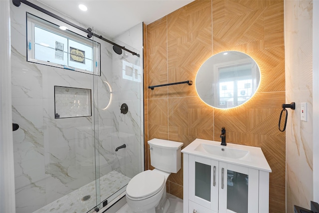 bathroom with tile walls, an enclosed shower, vanity, and toilet