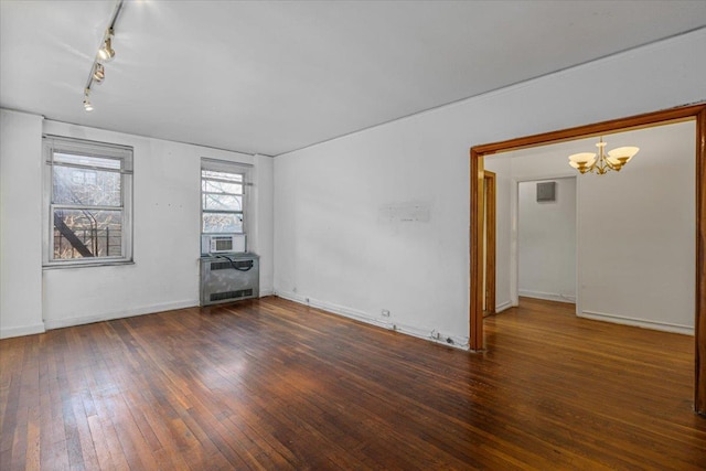 unfurnished room featuring a notable chandelier, rail lighting, radiator, and dark hardwood / wood-style floors