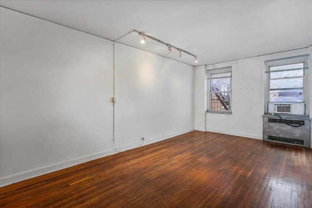 empty room with cooling unit, radiator heating unit, and dark hardwood / wood-style floors