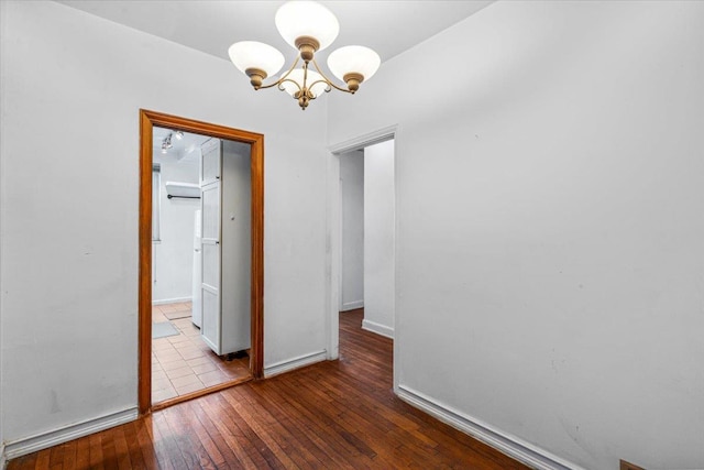 spare room with a notable chandelier and light hardwood / wood-style floors